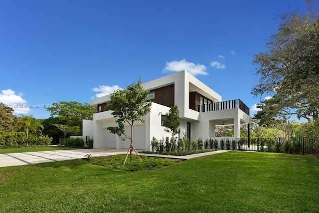 view of front of house with stucco siding, an attached garage, a front yard, a balcony, and driveway