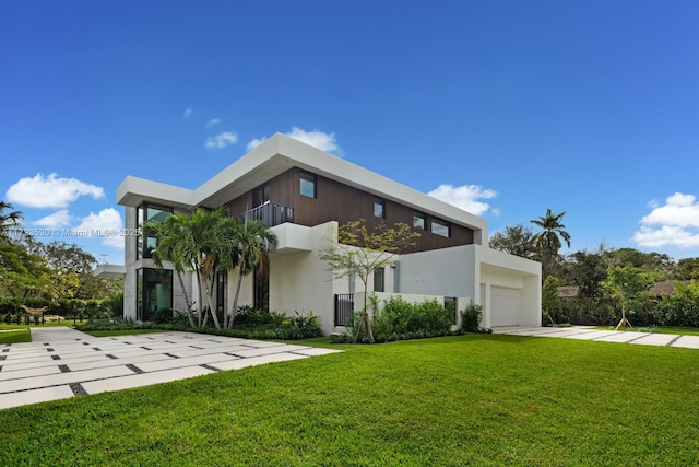 modern home featuring stucco siding, concrete driveway, an attached garage, a front yard, and a balcony