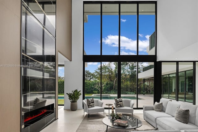 living room with a high ceiling and a wall of windows