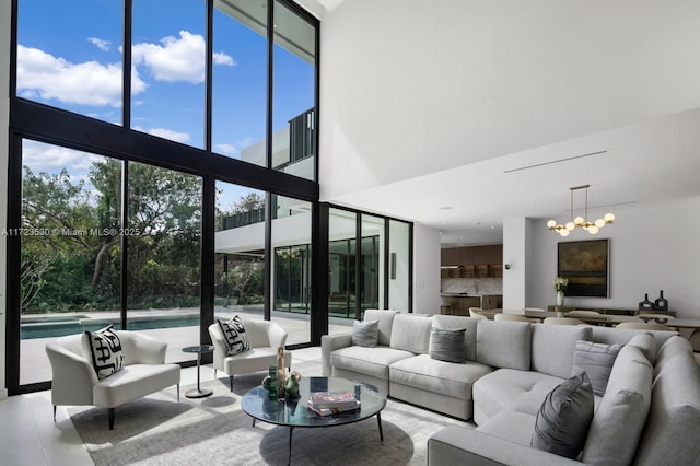 living room featuring floor to ceiling windows, plenty of natural light, a towering ceiling, and a notable chandelier