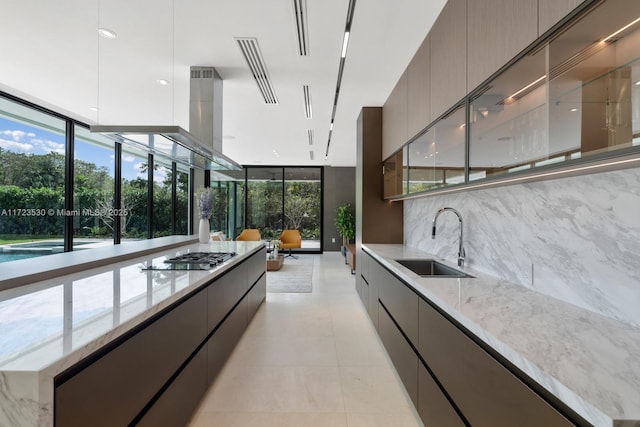 kitchen with a sink, a wall of windows, modern cabinets, and gas stovetop