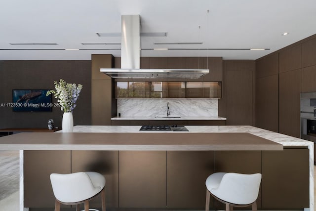 kitchen featuring cooktop, light countertops, a sink, and a kitchen breakfast bar