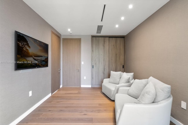 living room with baseboards, light wood-type flooring, visible vents, and recessed lighting