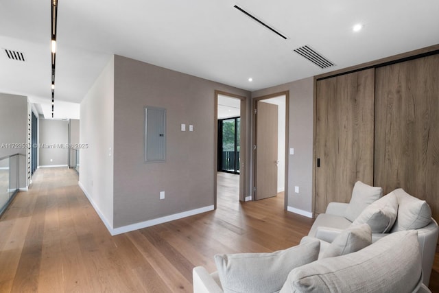 living area featuring light wood finished floors, electric panel, and visible vents