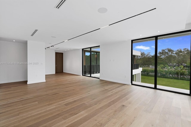 unfurnished room featuring light wood-type flooring, expansive windows, and baseboards