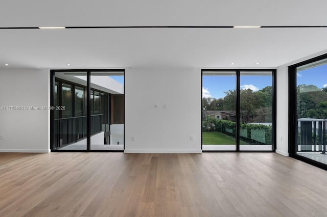 empty room featuring expansive windows, baseboards, wood finished floors, and recessed lighting