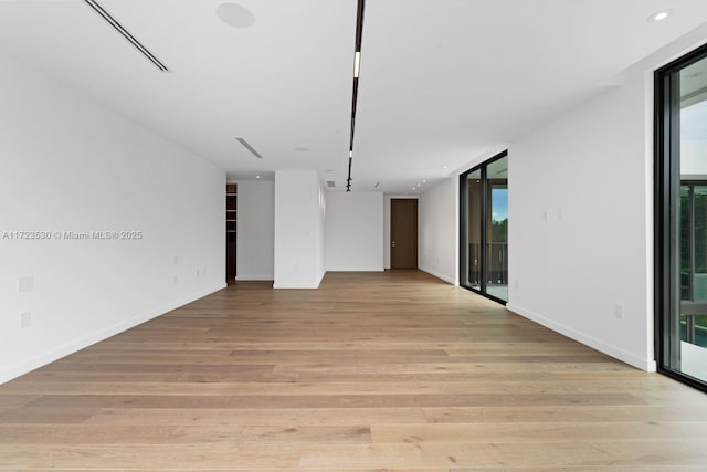 empty room with a wall of windows, recessed lighting, baseboards, and light wood finished floors