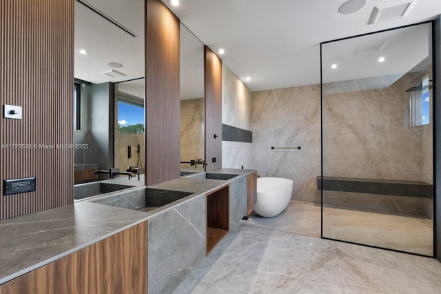 bathroom with a freestanding bath, tile walls, a sink, and double vanity