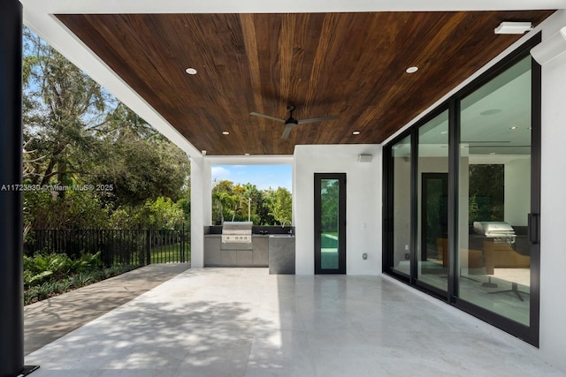 view of patio / terrace with exterior kitchen, grilling area, fence, and a ceiling fan