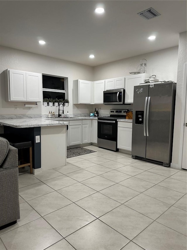 kitchen featuring sink, light tile patterned floors, kitchen peninsula, stainless steel appliances, and white cabinets