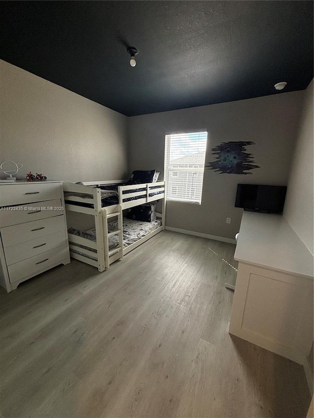 unfurnished bedroom featuring light wood-type flooring, baseboards, and a textured ceiling