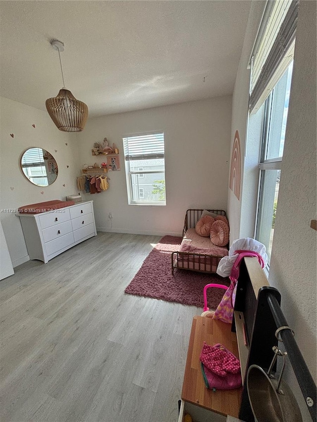 living area with a textured ceiling, baseboards, and wood finished floors