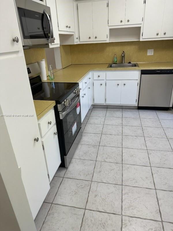 kitchen with sink, stainless steel appliances, light tile patterned floors, tasteful backsplash, and white cabinets