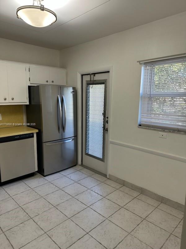 kitchen featuring white cabinets, stainless steel appliances, and light tile patterned floors