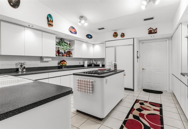 kitchen featuring white cabinets, a kitchen island, paneled refrigerator, and light tile patterned floors