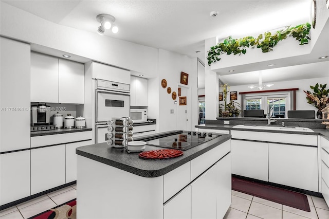 kitchen with white double oven, a center island, sink, black electric cooktop, and white cabinets