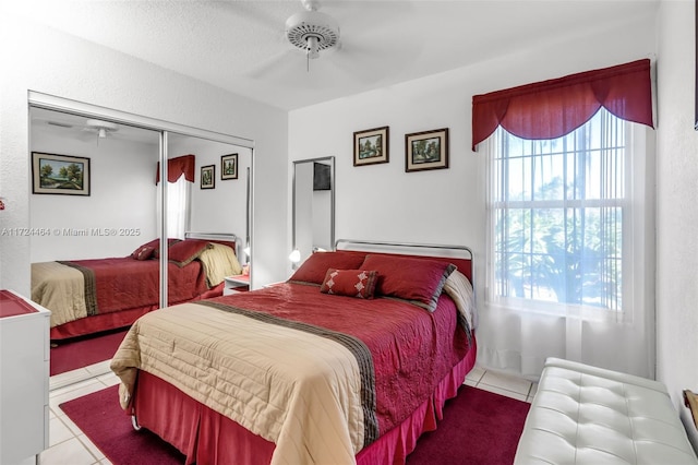 bedroom featuring ceiling fan, light tile patterned floors, and a closet