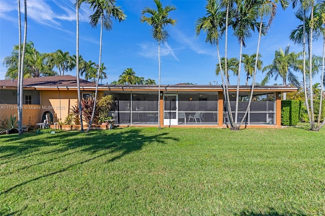 rear view of house featuring a lawn and a sunroom