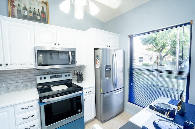 kitchen featuring tasteful backsplash, white cabinetry, light tile patterned flooring, and appliances with stainless steel finishes