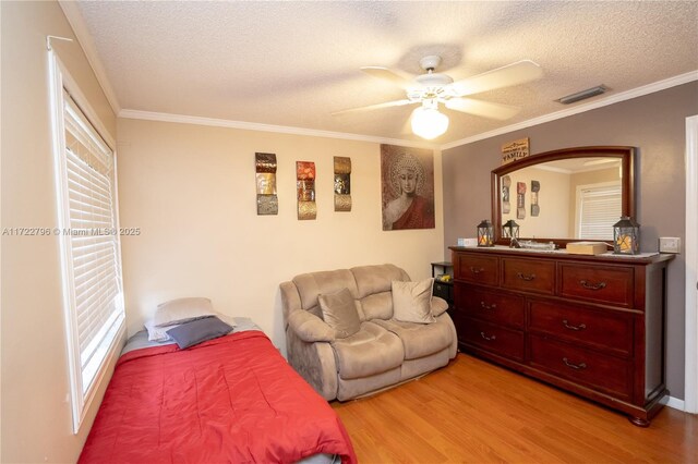 bedroom with ceiling fan, ornamental molding, a textured ceiling, and light hardwood / wood-style flooring