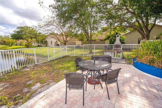 view of patio with a water view and an outdoor fireplace