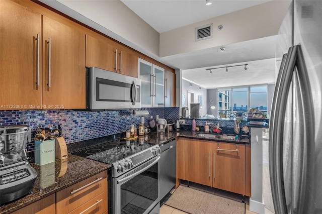 kitchen with tasteful backsplash, stainless steel appliances, sink, dark stone countertops, and light tile patterned flooring