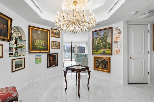 hallway with a notable chandelier and a raised ceiling