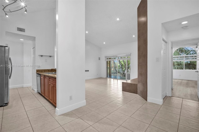 kitchen with light stone countertops, light tile patterned floors, high vaulted ceiling, and appliances with stainless steel finishes