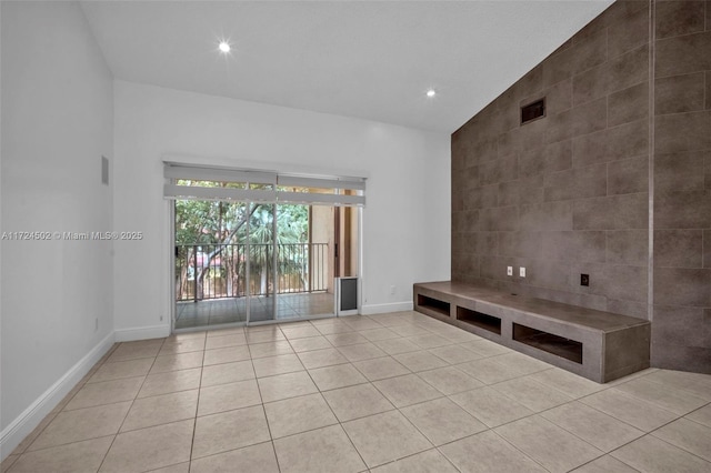 unfurnished living room featuring high vaulted ceiling and light tile patterned flooring