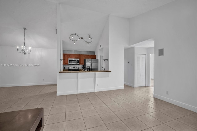 unfurnished living room featuring light tile patterned floors, high vaulted ceiling, and an inviting chandelier