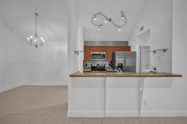 kitchen with stone counters, vaulted ceiling, decorative light fixtures, light tile patterned flooring, and appliances with stainless steel finishes