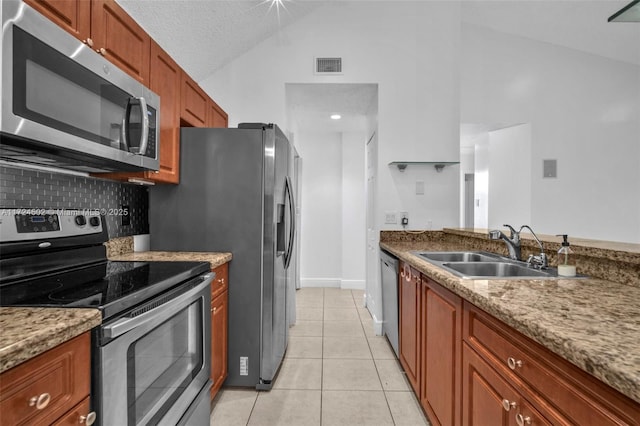 kitchen featuring light tile patterned floors, lofted ceiling, sink, and appliances with stainless steel finishes