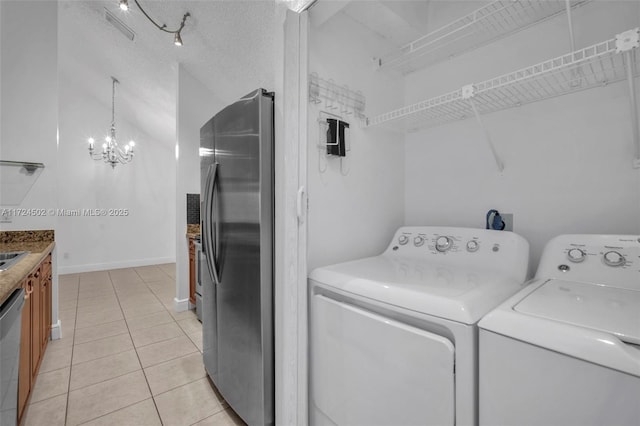 laundry room with washer and dryer, light tile patterned floors, a textured ceiling, and a notable chandelier