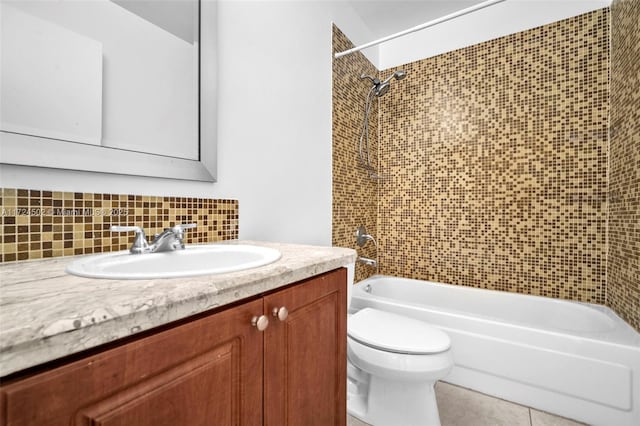 full bathroom with vanity, backsplash, tile patterned floors, tiled shower / bath, and toilet