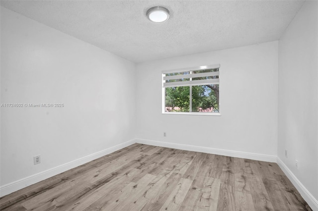 unfurnished room with a textured ceiling and light hardwood / wood-style floors