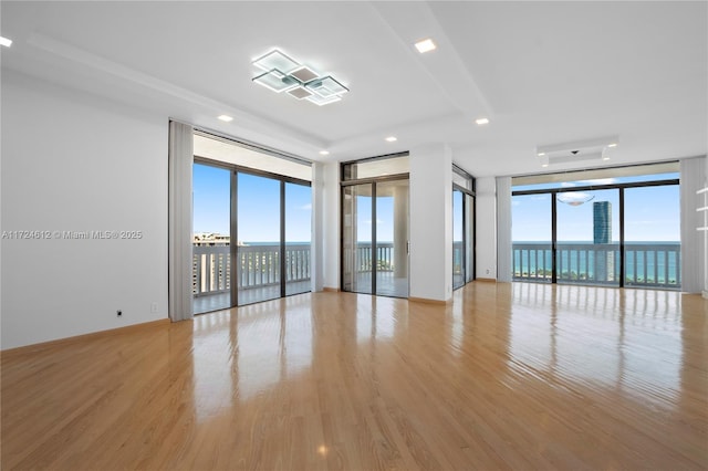 unfurnished room featuring light hardwood / wood-style floors, expansive windows, and a water view