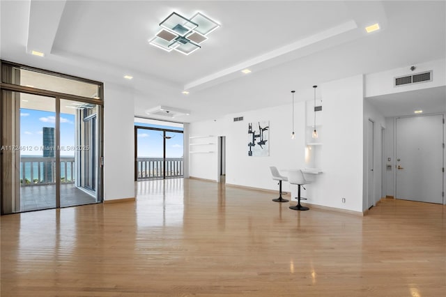 empty room with floor to ceiling windows and light hardwood / wood-style flooring