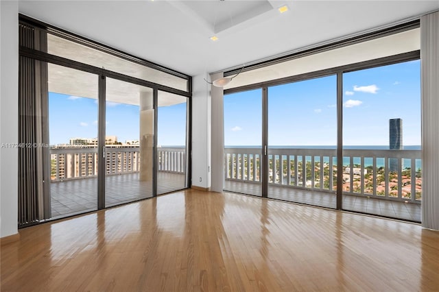 spare room with hardwood / wood-style flooring, expansive windows, and a water view