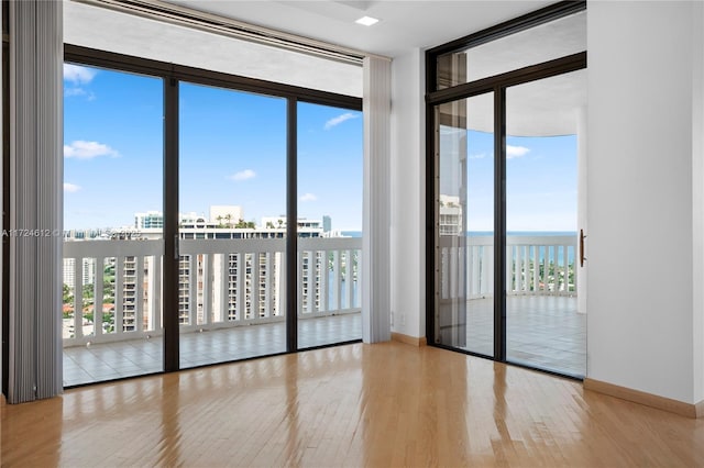 empty room featuring light wood-type flooring, floor to ceiling windows, and a water view