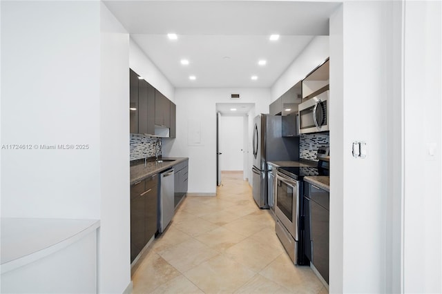 kitchen featuring appliances with stainless steel finishes, dark brown cabinets, decorative backsplash, and light tile patterned floors