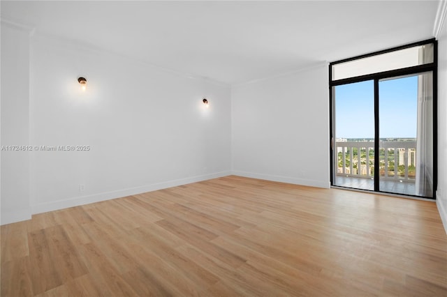 empty room featuring light hardwood / wood-style floors, ornamental molding, and floor to ceiling windows