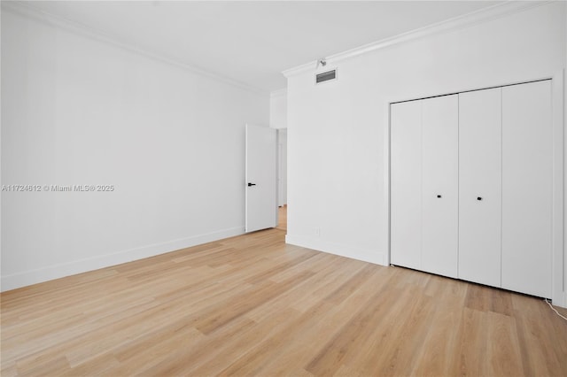 unfurnished bedroom with light wood-type flooring, ornamental molding, and a closet