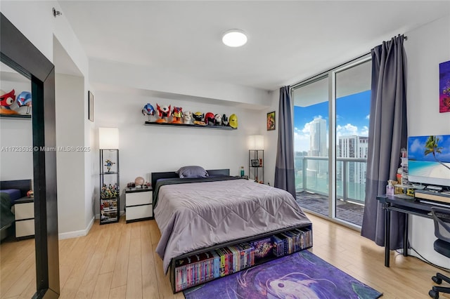 bedroom featuring access to outside, floor to ceiling windows, and light wood-type flooring