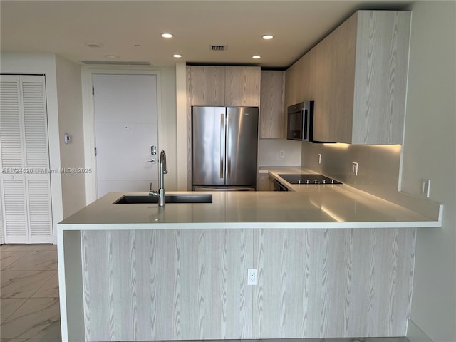 kitchen featuring sink, decorative backsplash, light brown cabinetry, kitchen peninsula, and stainless steel refrigerator