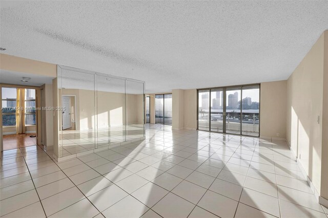 spare room featuring a textured ceiling, light tile patterned floors, and expansive windows