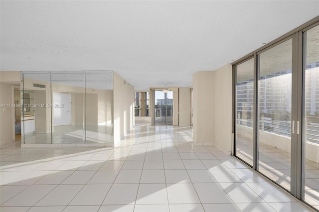 tiled empty room with a textured ceiling, ceiling fan, and floor to ceiling windows