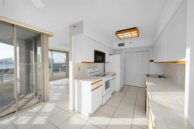 kitchen featuring tile countertops, decorative backsplash, white appliances, and white cabinetry