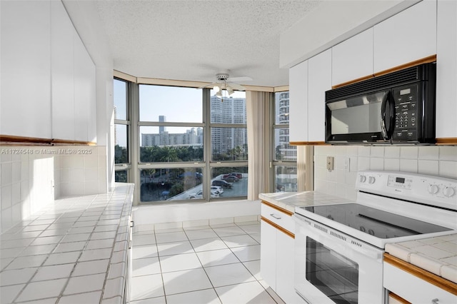 kitchen with light tile patterned floors, tile counters, white electric range, a textured ceiling, and white cabinets