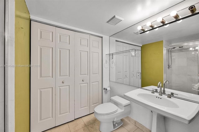 bathroom featuring a shower with shower door, tile patterned floors, and toilet