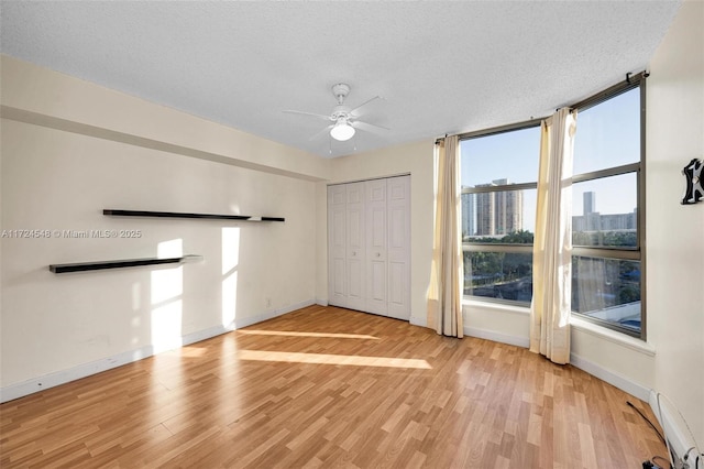 empty room featuring a textured ceiling, light hardwood / wood-style flooring, and a healthy amount of sunlight